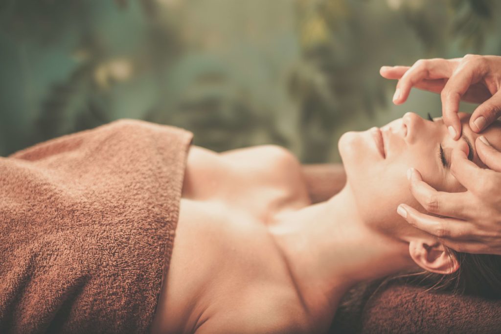 Young woman having face massage in a spa salon.